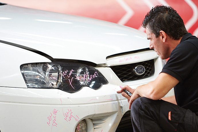 Capital SMART estimator inspecting front-end damage marked for repair